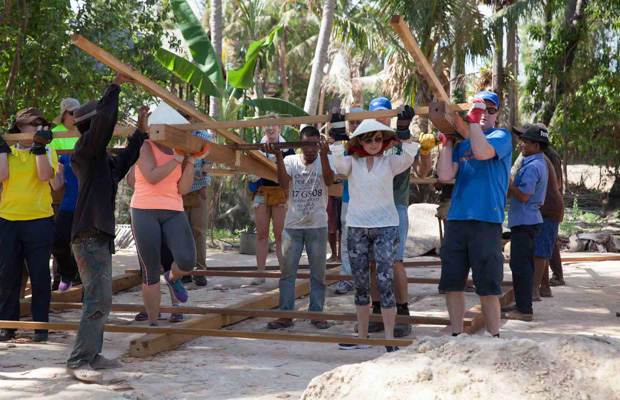 Volunteers lift the house frame of a VBC house